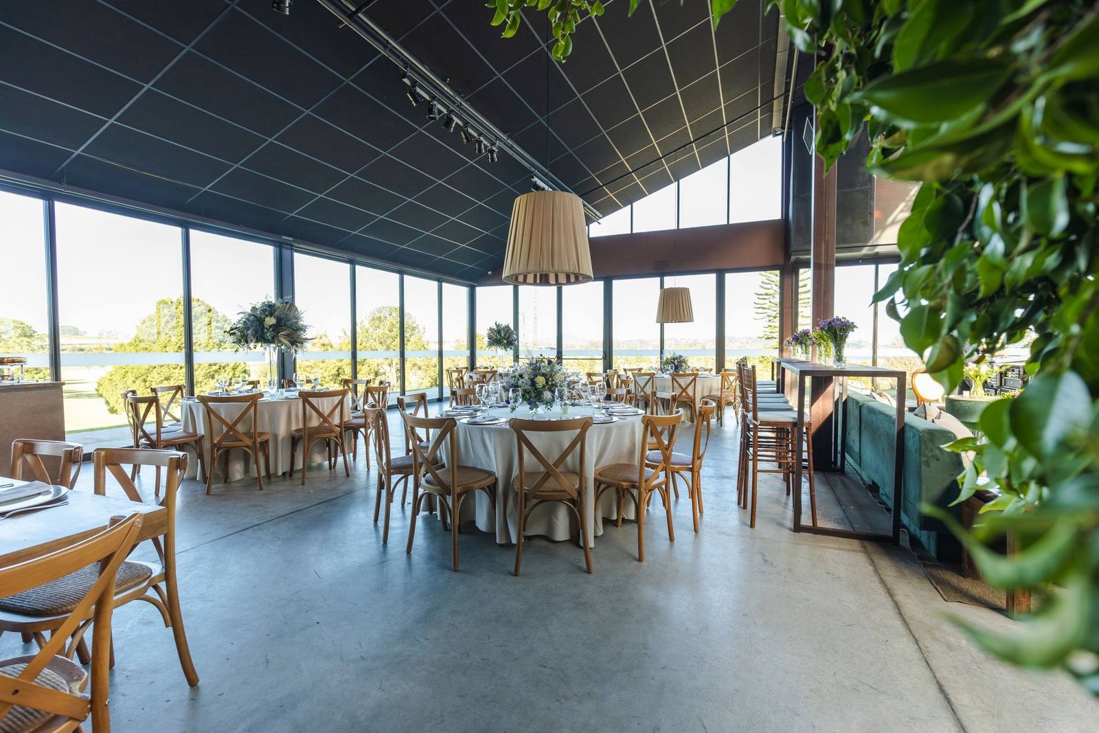 Sala per ricevimenti con tavoli rotondi apparecchiati davanti a una vetrata sul verde